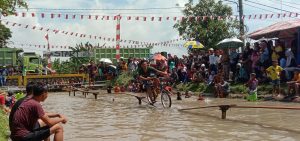 Meriahkan HUT RI ke-77, Warga Serdang Bedagai Uji Nyali Bersepeda Lintasi Selembar Papan di Atas Sungai