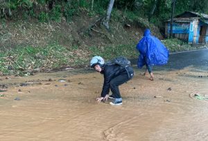 Kondisi ruas Jalan Cibeber-Sukanagara yang rusak dibersihkan oleh seorang mahasiswa kader GMNI Cianjur.