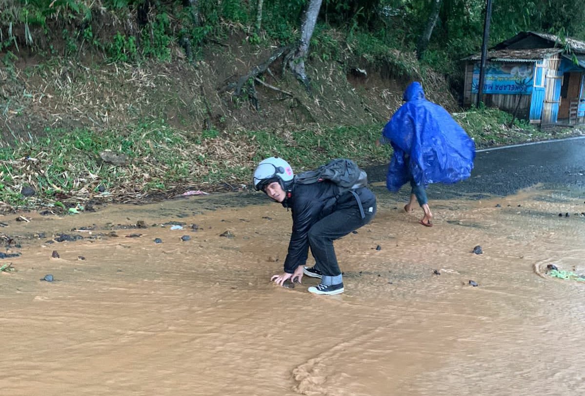 Kondisi ruas Jalan Cibeber-Sukanagara yang rusak dibersihkan oleh seorang mahasiswa kader GMNI Cianjur.