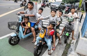 Sejumlah anak-anak menggunakan sepeda listrik di jalan raya.