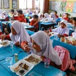 Para siswa menikmati menu yang disajikan dalam program makan bergizi gratis