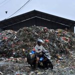Pengendara melintasi di tumpukan sampah di kawasan Pasar Caringin (1)