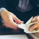 Pengusaha menghitung uang hasil penjualan dari platform digital PaDi UMKM yang bantu tingkatkan omzet hingga miliaran rupiah per tahun.