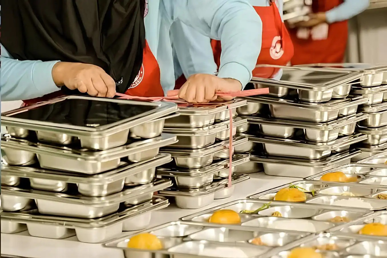 Petugas menyiapkan paket Makan Bergizi Gratis (MBG) untuk didistribusikan ke anak-anak selama libur sekolah.