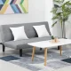 Sofa bed minimalis kain abu-abu di ruang tamu modern dengan meja kayu dan dekorasi tanaman.