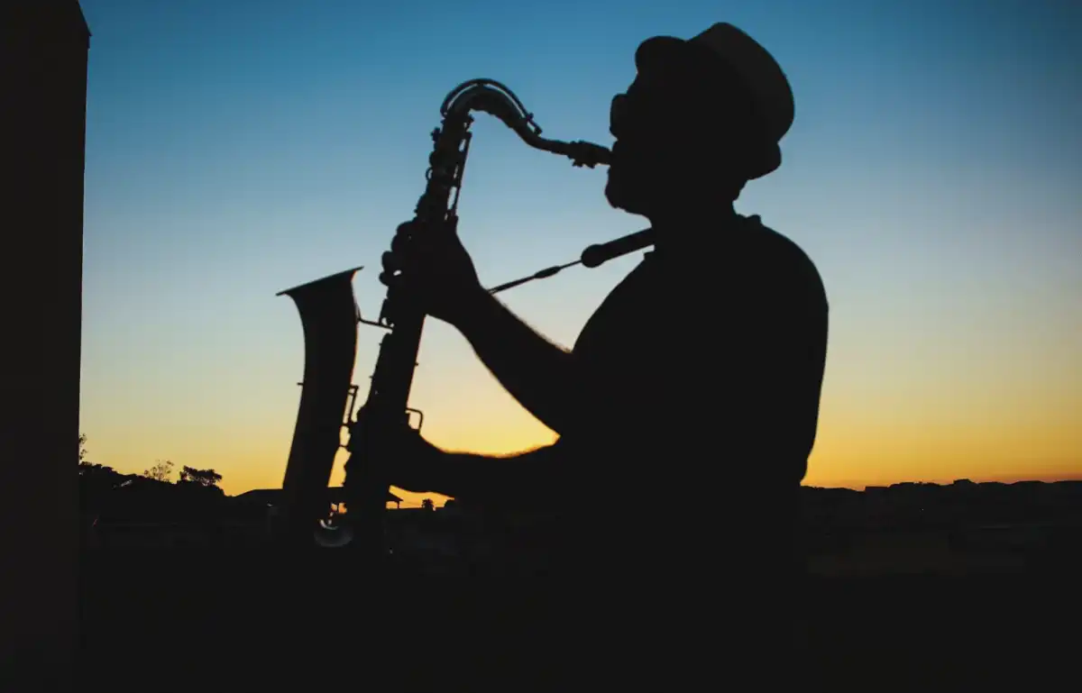 Siluet pemain saksofon tampil di panggung terbuka saat matahari terbenam, menggambarkan atmosfer BRI Jazz Gunung Bromo 2025.