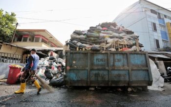 Petugas kebersihan menangani sampah yang menumpuk di salah satu titik di Kota Bandung.