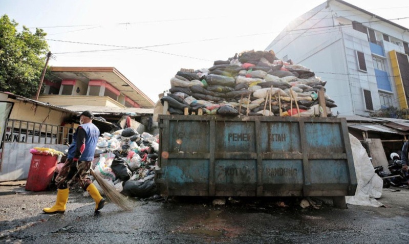 Petugas kebersihan menangani sampah yang menumpuk di salah satu titik di Kota Bandung.