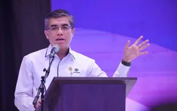 Pengemudi ojol sedang mengecek ponsel, ilustrasi diskon iuran BPJS Ketenagakerjaan 50 persen bagi pekerja mandiri.